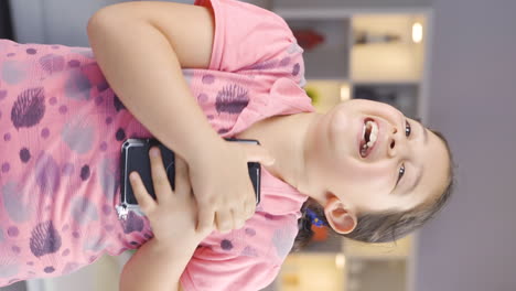 Vertical-video-of-The-girl-child-who-happily-puts-the-phone-to-her-heart.